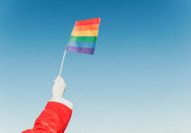 Santa Claus Hand Holding A Lgbt Pride Flag With Clear Blue Sky I