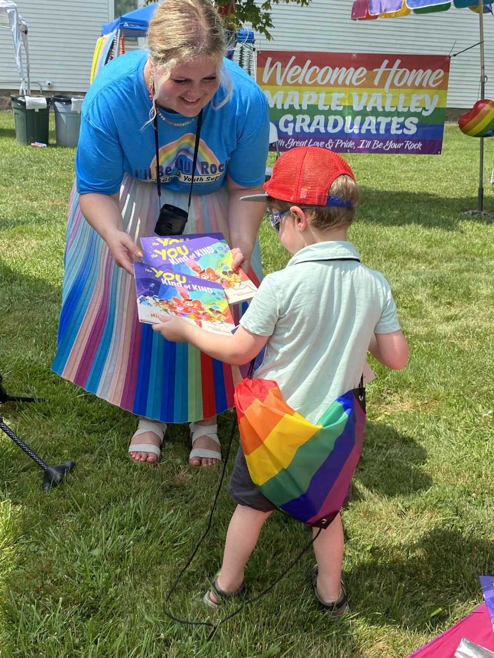 Cassey Tien offers an LGBTQ-affirming book to a Vermontville Youth Pride attendee. Courtesy photo