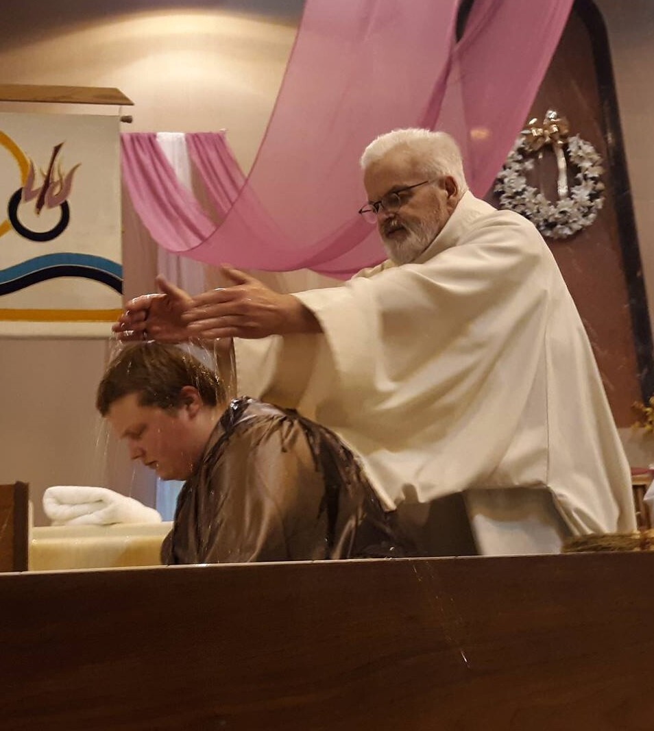 Claude Johnson-Perry's baptismal service with Father Bill Lugger. Courtesy photo