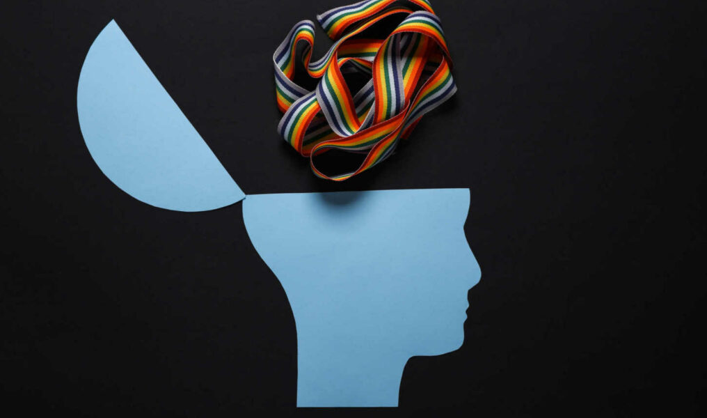 Open your mind, mental health concept, creative thinking. Paper silhouette of human head and lgbt rainbow tape on black background