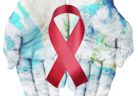 World map on hands with red ribbon on white background , world aids day concept
