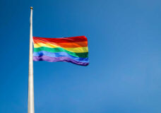Gay pride rainbow flag flying at half mast in mourning on bright