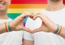 gay couple with rainbow wristbands and hand heart