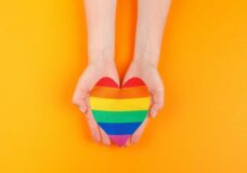 Gay Love. Human Hand Holding A Rainbow Paper Heart
