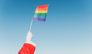 Santa Claus Hand Holding A Lgbt Pride Flag With Clear Blue Sky I