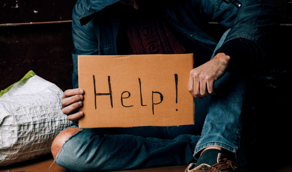 A Homeless Person Holds A Sign , Asks For Work, And Seeks Help.