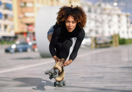Black woman on roller skates riding outdoors on urban street