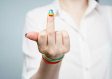 Photo of girl with rainbow nails showing middle finger