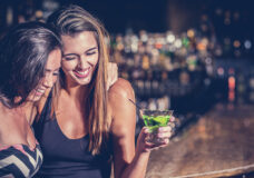 Two young woman having martinis laughing