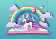 Open fairy tale book with unicorn, rainbow and mountain landscape. Cut out paper art style design