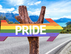 Pride in a Rainbow wooden sign with a street background