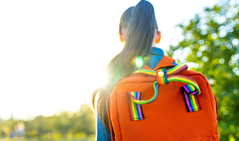 girl student wears backpack outdoors in summer park