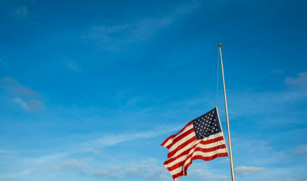 American Flag at Half Mast after another School Shooting wide angle view with Flag lowered on Flagpole